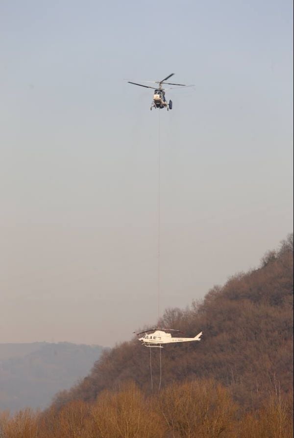 Recuperan el helicóptero de la BRIF de Tabuyo que cayó al río Narcea en Belmonte cuando trabaja en la extinción de un incendio forestal | Ha sido izado por otra aeronave, que lo ha depositado en tierra, donde se trabaja en el desmontaje de las hélices para su evacuación