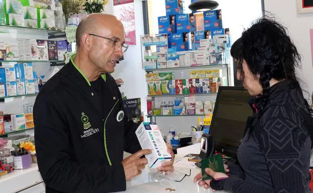 Javier Furones atiende a una paciente en su farmacia de la calle Estación. :: 