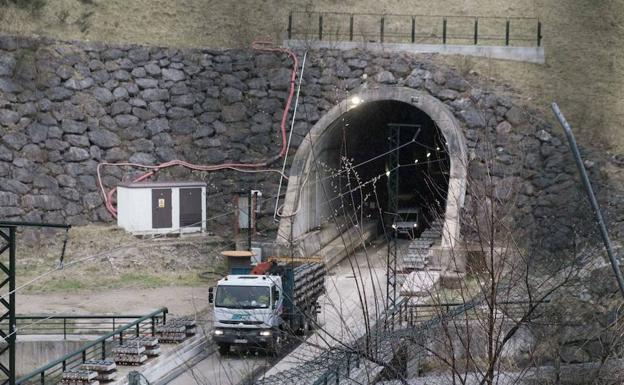 Camiones y furgonetas maniobran marcha atrás en uno de los túneles de la variante de Pajares para llevar las vías al interior.