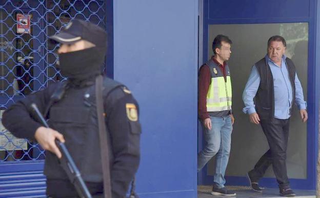 El presidente del Huesca, Agustín Lasaosa,d., junto a un policia a su salida de las oficinas del club tras ser detenido durante la «Operación Oikos» contra el presunto amaño de partidos de fútbol en Primera y Segunda División.