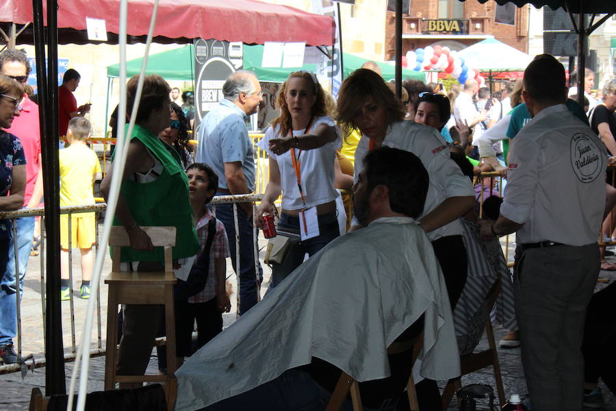 La céntrica plaza de San Marcelo se ha convertido en la jornada del domingo en un improvisado salón de belleza, en el que peluqueros, barberos, tatuadores, maquilladores y masajistas se han puesto a trabajar bajo la iniciativa 'León te corta' promovida por Víctor Valín en favor de la AECC