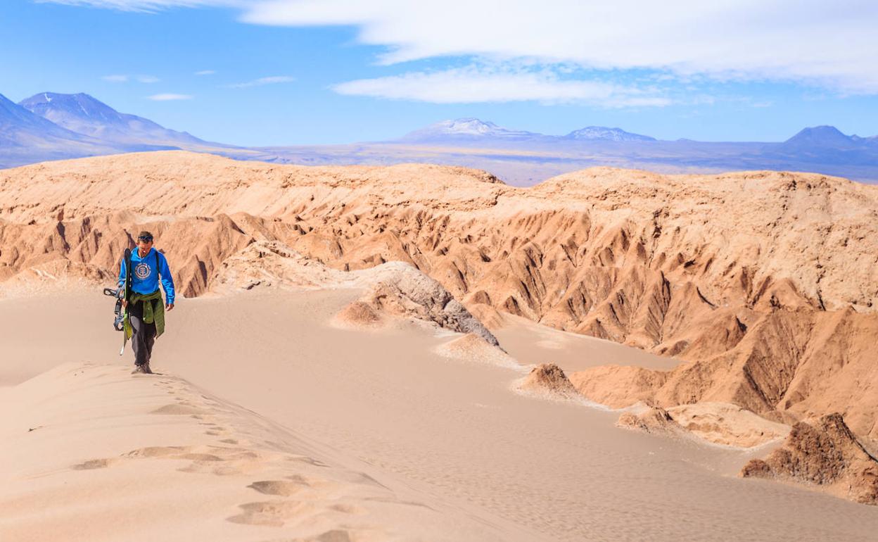 Un hombre pasea por el desierto de Atacama antes de practicar 'sandboard'. 