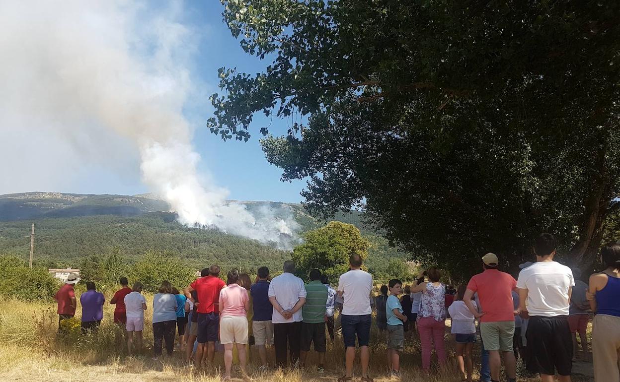 Un grupo de personas observan la columna de humo. 