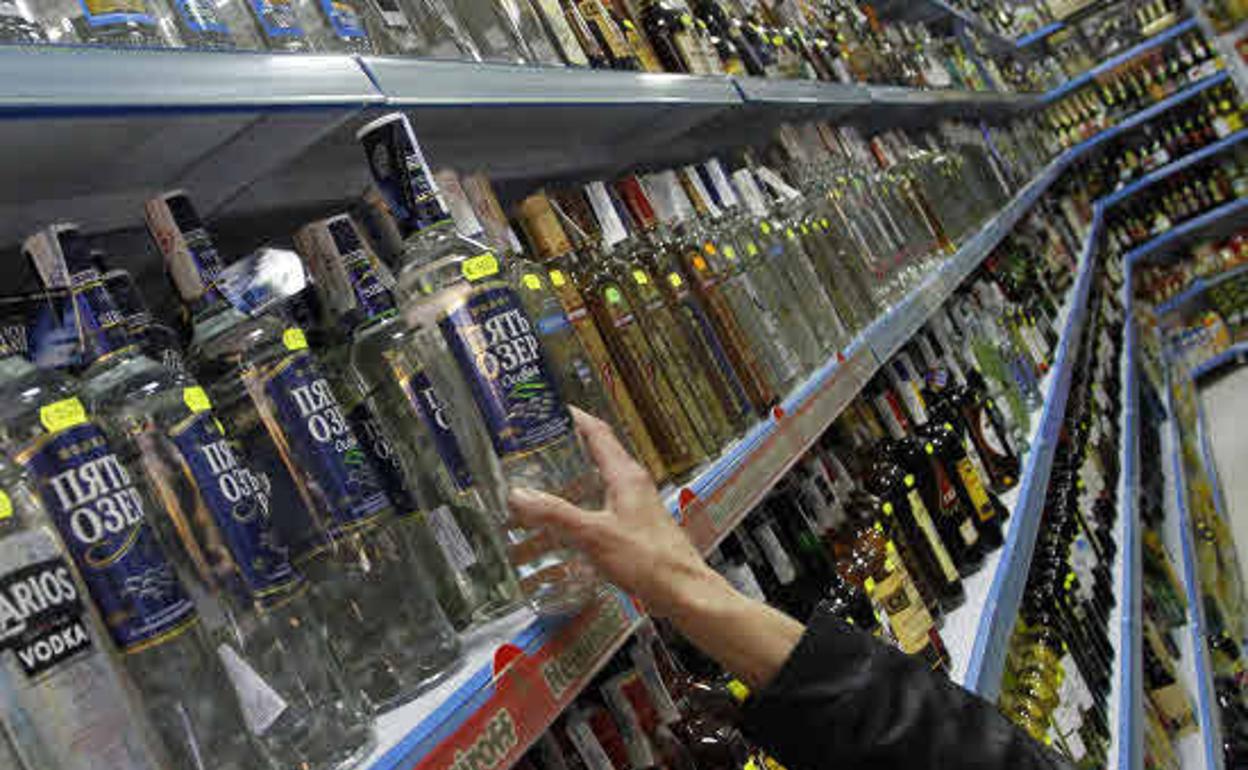 Una persona coge una botella de vodka en un supermercado ruso. 