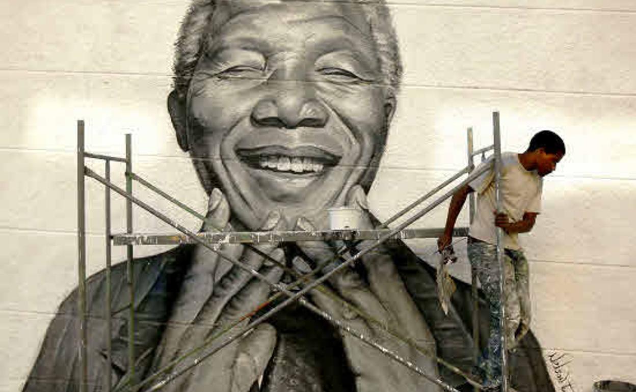 Grafitero pinta a Nelson Mandela en la fachada de un edificio en Lisboa.