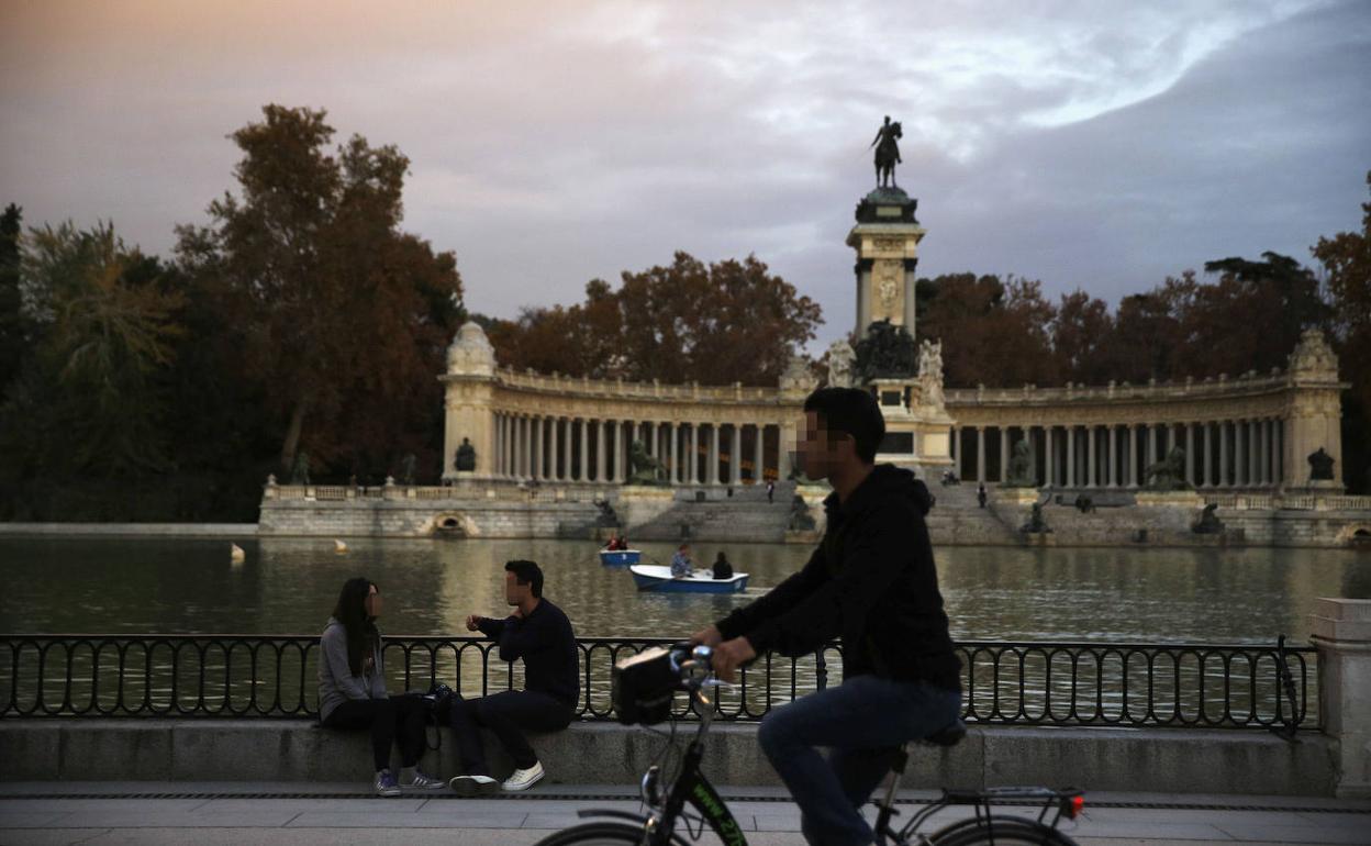 Un joven pasea en bicicleta en paseo del lago del parque madrileño de El Retiro.