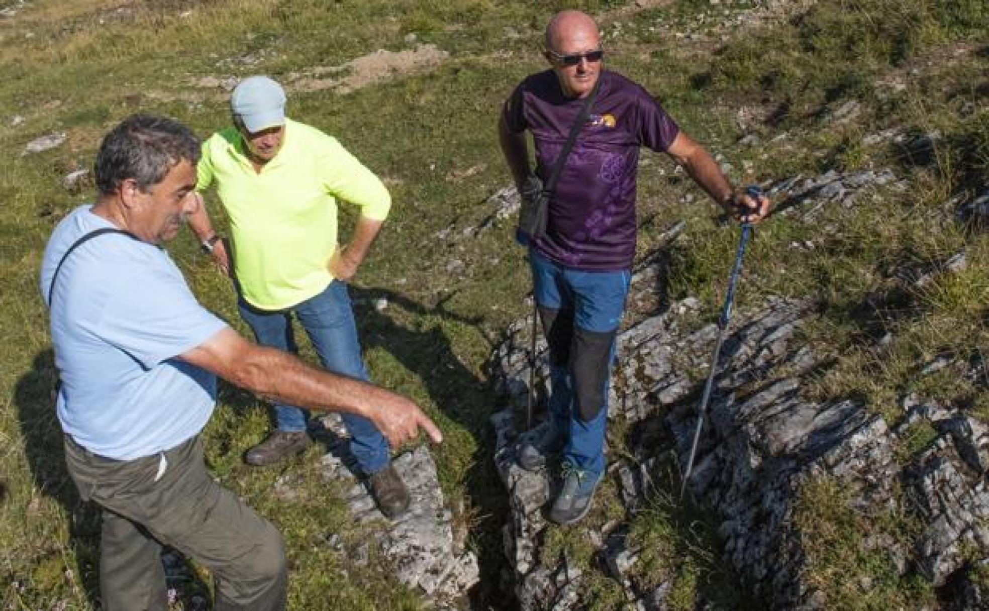 En la torca, José Collado, amigo de la familia, señala hacia la sima en presencia de José Rodríguez y José Manuel Fernández, nietos de Eloy.. 