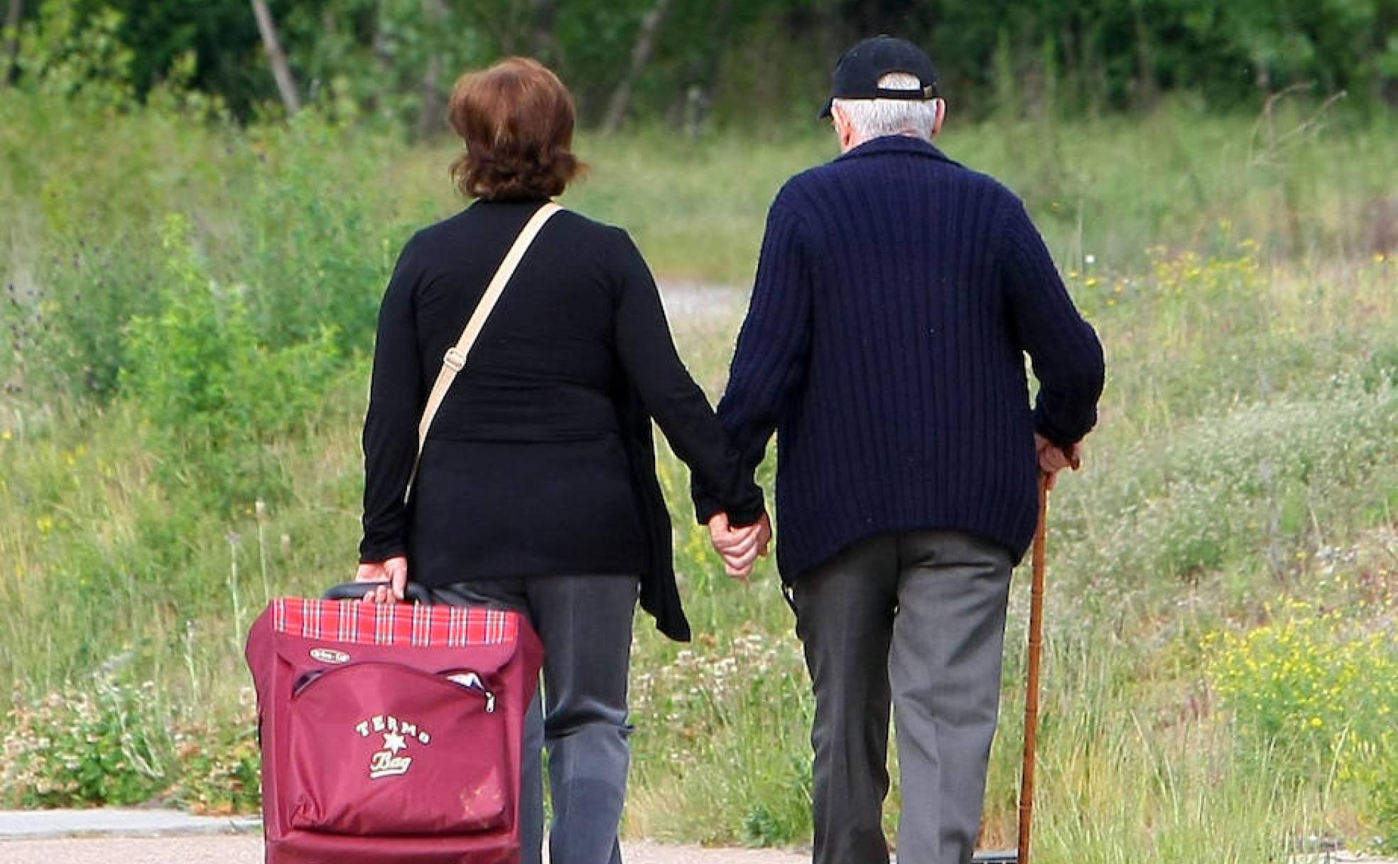 Una pareja de personas mayores pasea de la mano.