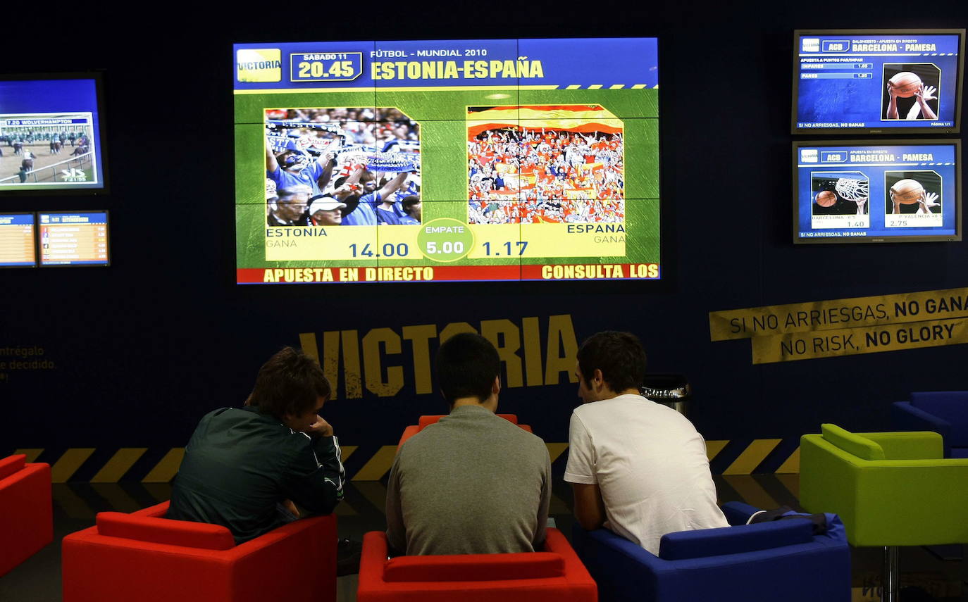 Tres jóvenes en una casa de apuestas de Madrid antes de un partido de España.