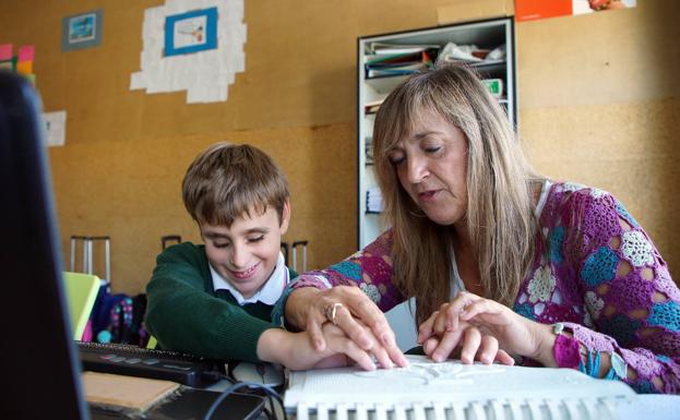 El alumno ciego Jorge Martínez estudia una lámina troquelada de anatomía en su clase del colegio de las Jesuitinas junto a su maestra de apoyo de la Once María Jesús Palomera. 