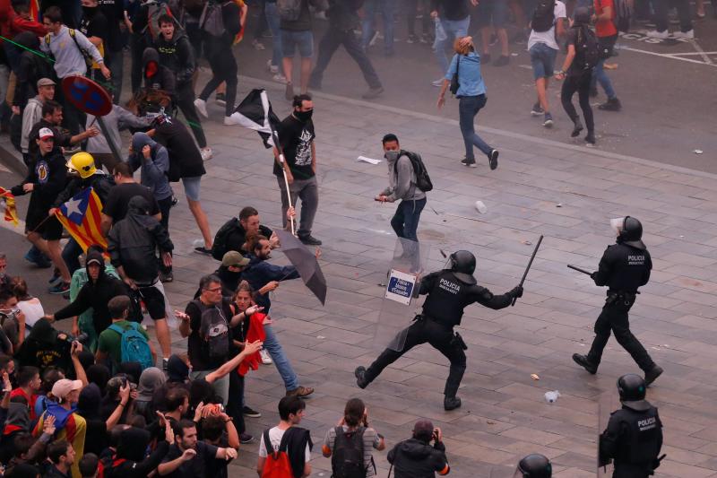 Miembros de los Mossos d'Esquadra cargan contra los centenares de personas que se agolpan ante el Aeropuerto del Prat 