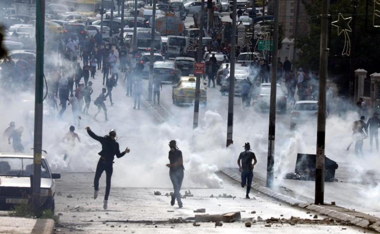 Varias personas palestinas se manifiestan mientras las Fuerzas Israelíes les lanzan gases lacrimógenos.