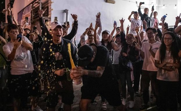 Manifestantes prodemocracia celebran con champán los resultados de los comicios locales junto a un colegio electoral.