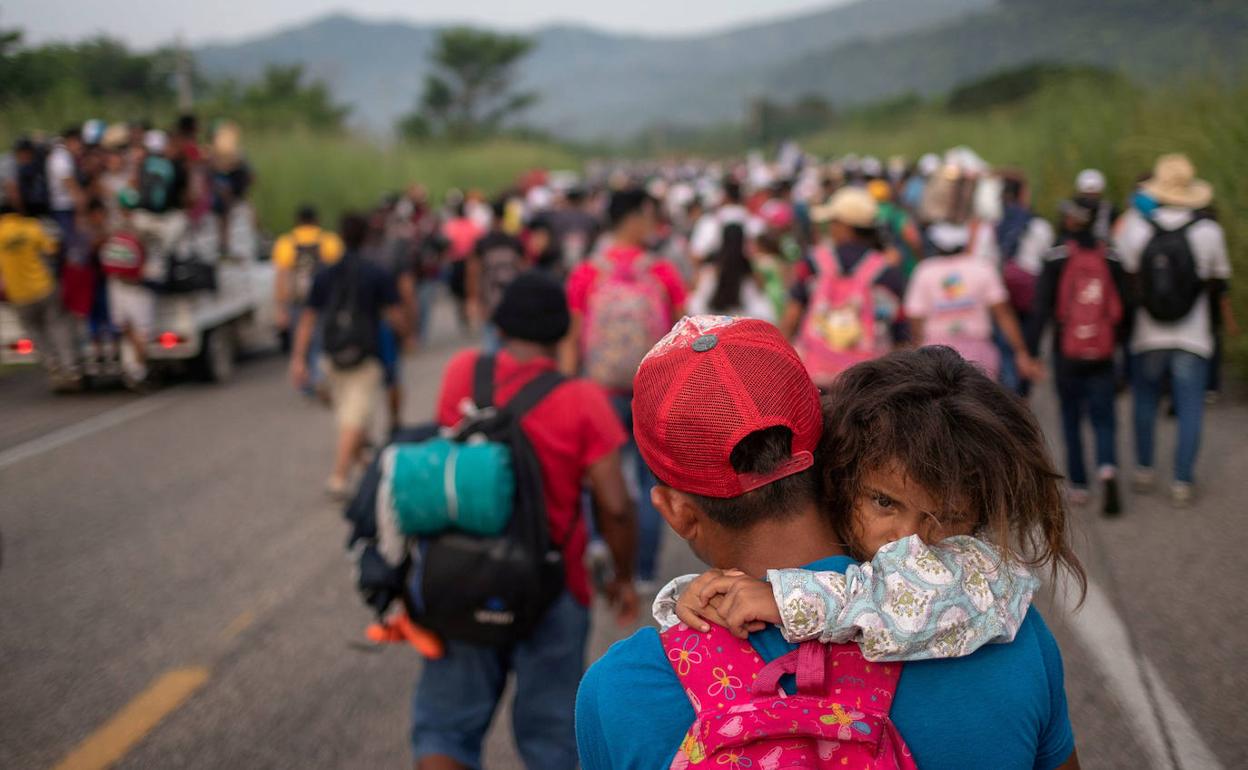 Migrante de Honduras lleva a su hija en medio de una caravana desde América Central a los Estados Unidos.