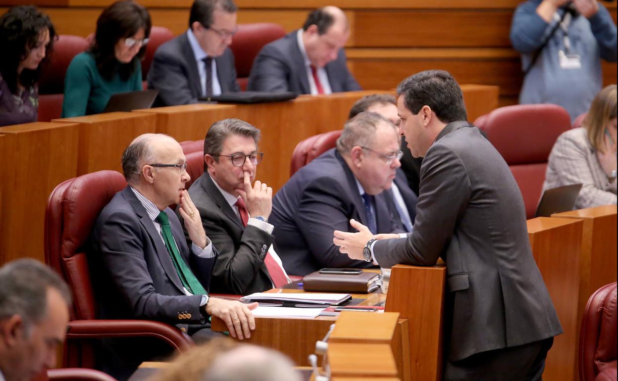 El portavoz del Grupo Popular, Raúl de la Hoz, conversa con el procurador popular Ramiro Ruiz Medrano durante el Pleno de las Cortes.