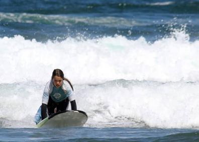 Imagen secundaria 1 - María, sobre su tabla de surf, en San Juan de la Arena, Asturias.