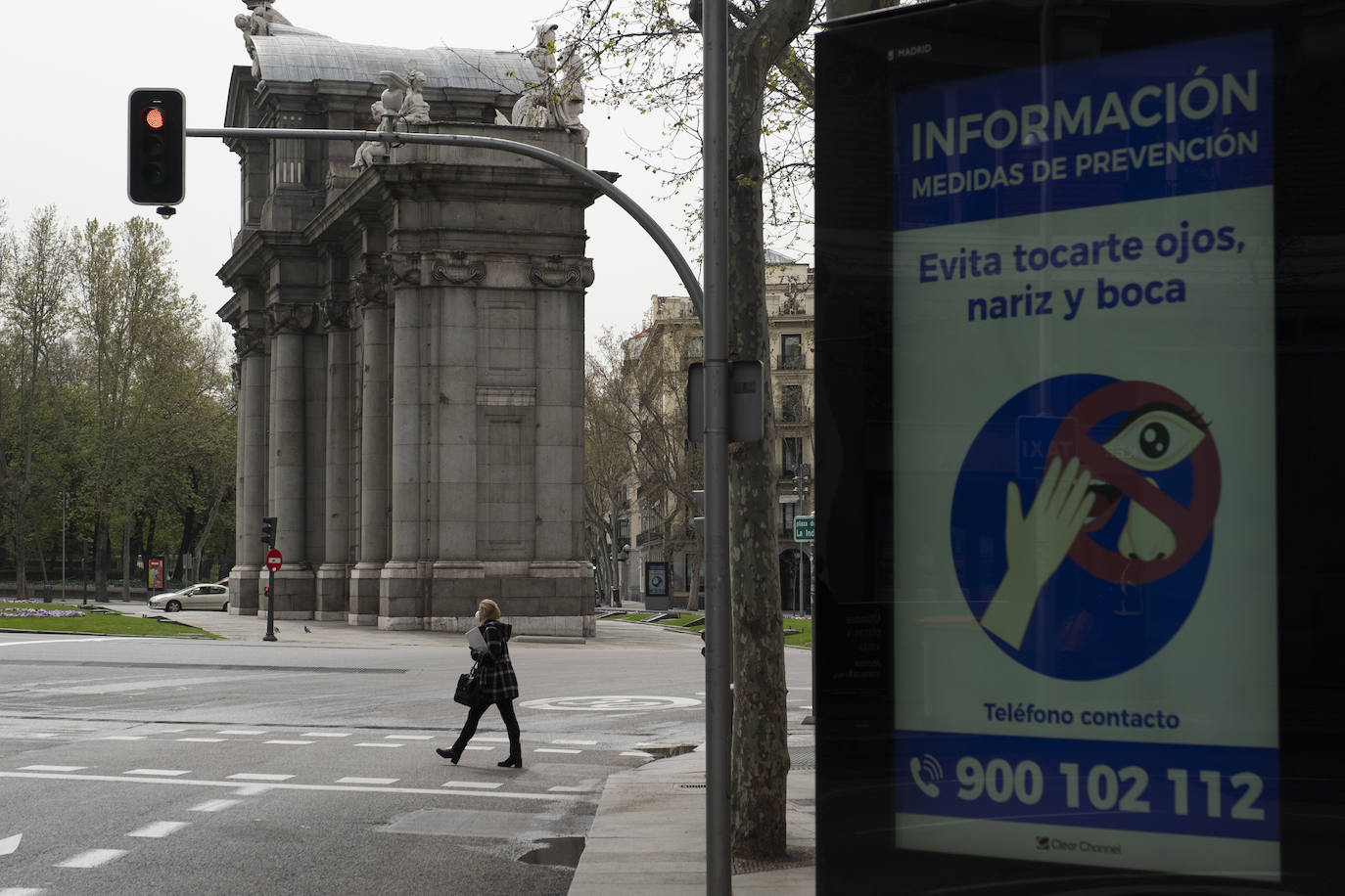 Una mujer cruza un paso de cebra junto a la Puerta de Alcalá 