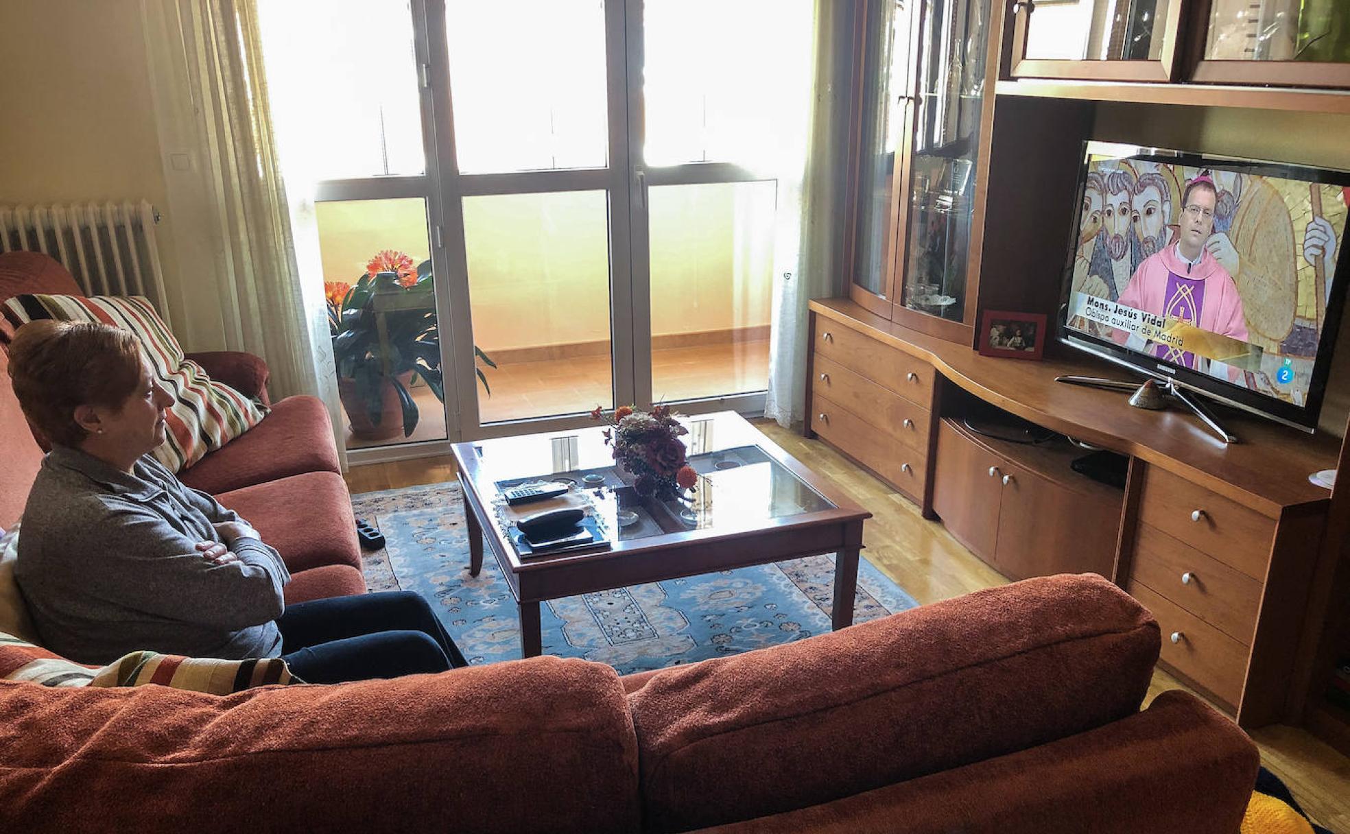 Una feligresa sigue la misa por la televisión.