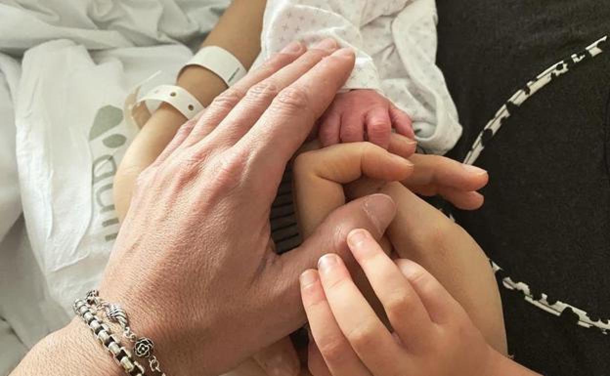 Manuel Carrasco, Almudena Navalón y Chloe unen sus manos con el recién nacido.