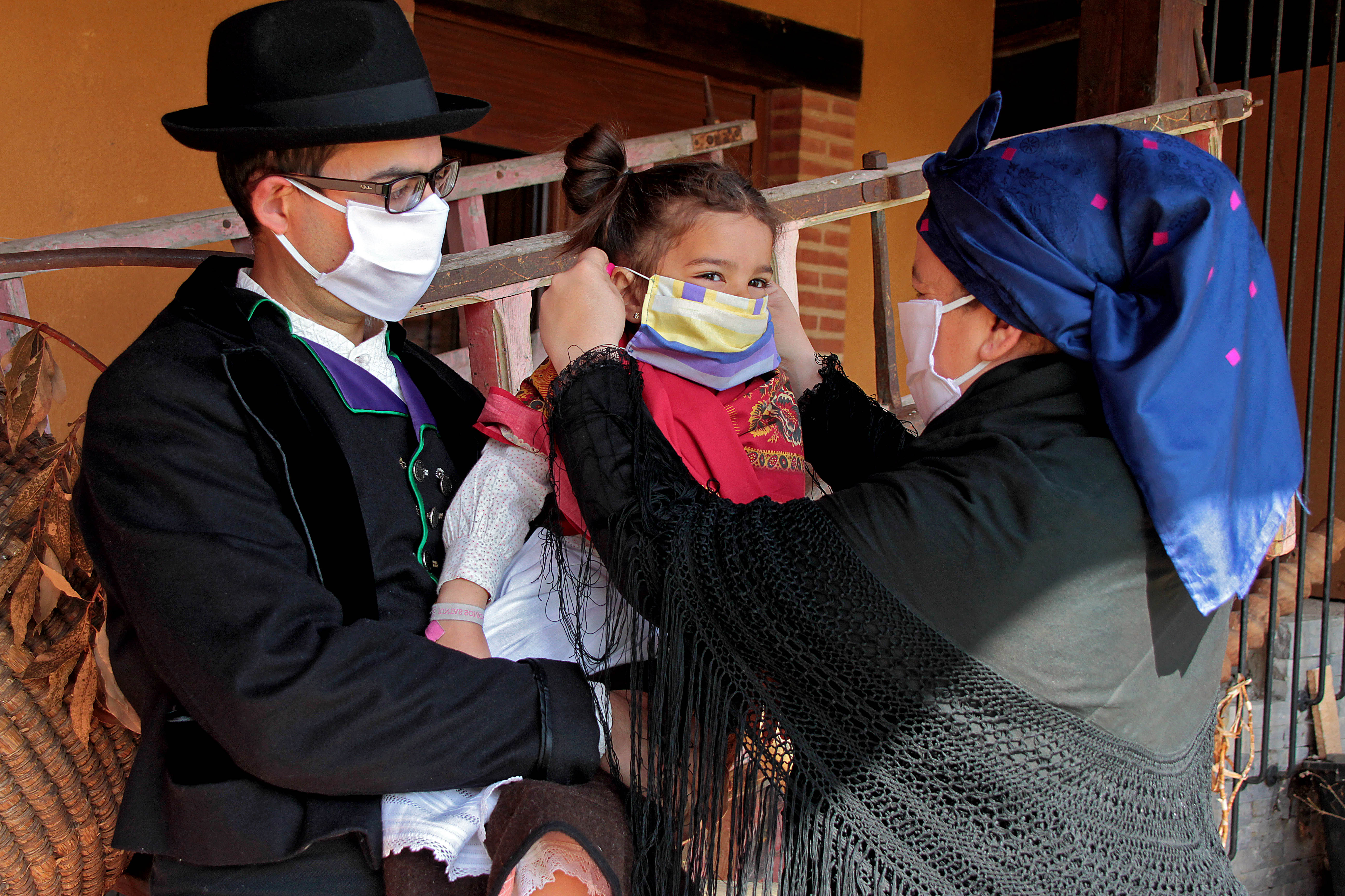 Un matrimonio y su hija, vestidos con indumentaria tradicional leonesa, se protegen contra la infección del coronavirus en Carrizo.