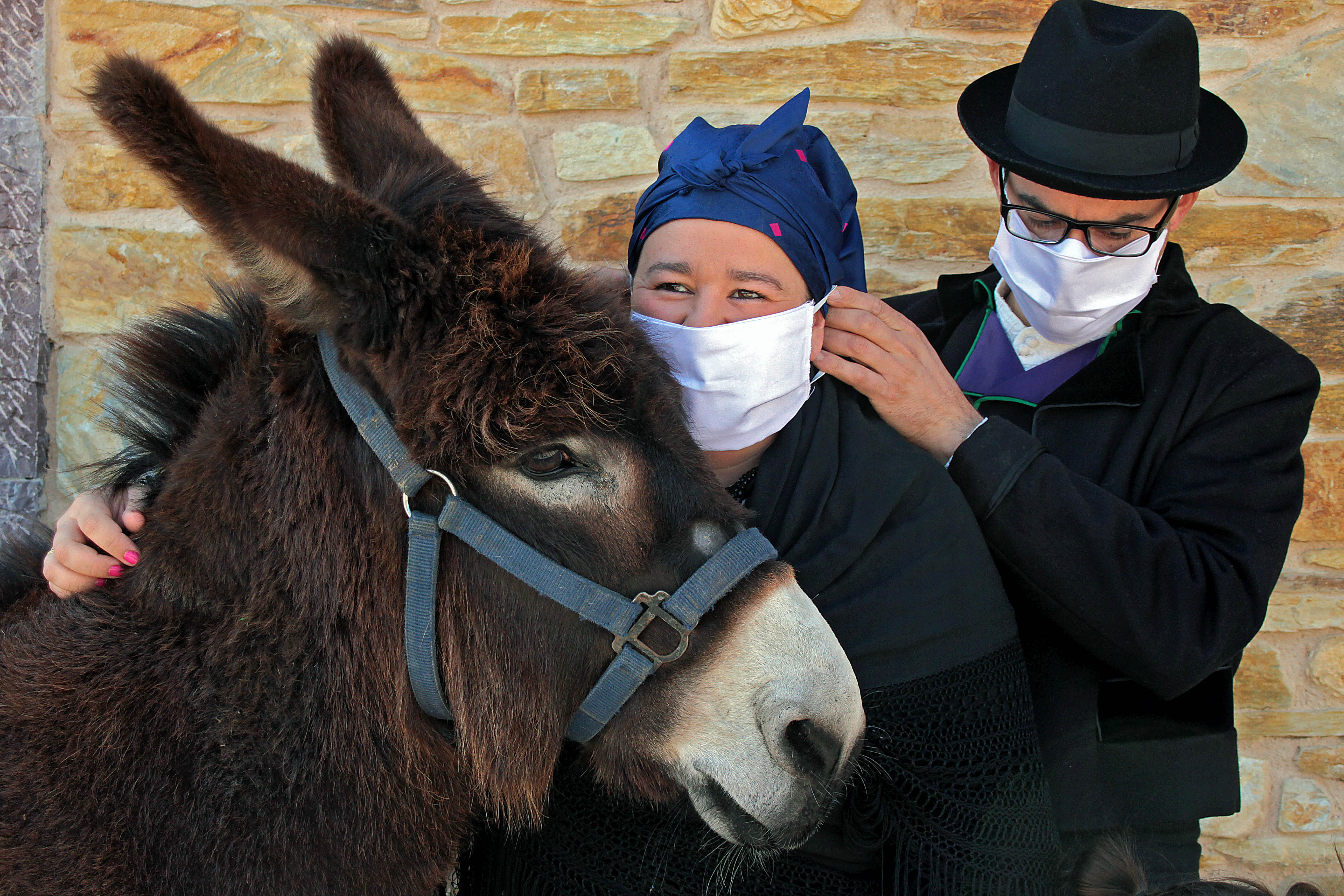 Un matrimonio y su hija, vestidos con indumentaria tradicional leonesa, se protegen contra la infección del coronavirus en Carrizo.