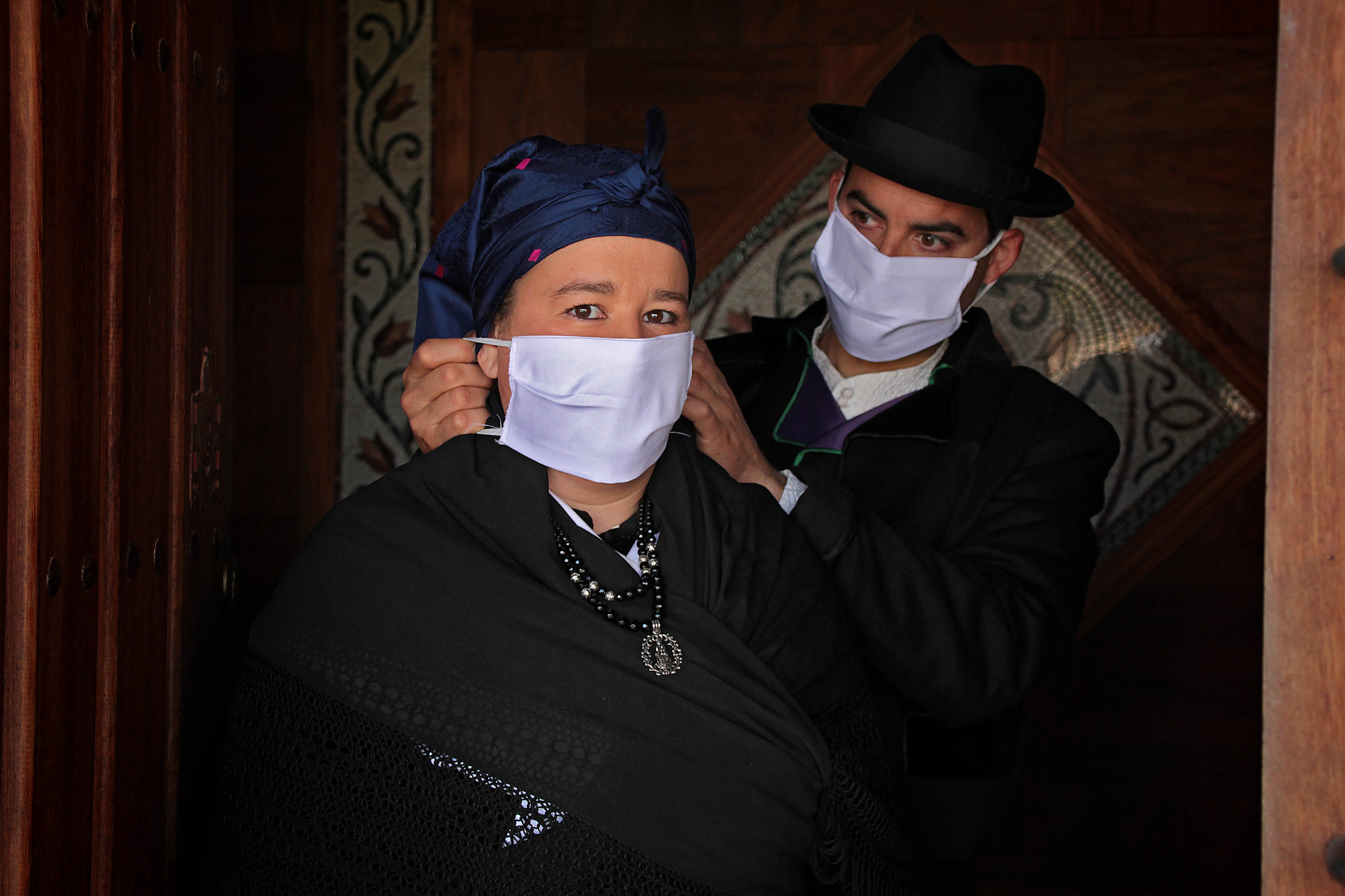 Un matrimonio y su hija, vestidos con indumentaria tradicional leonesa, se protegen contra la infección del coronavirus en Carrizo.