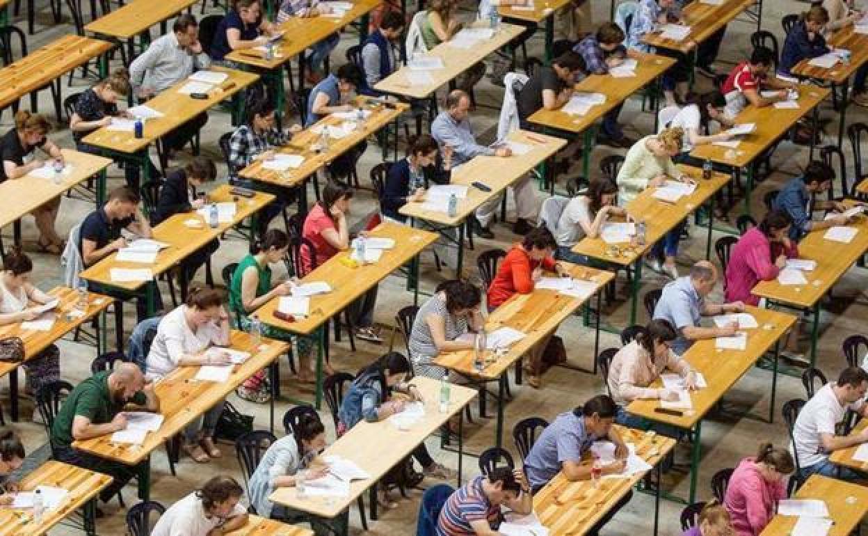 Oposiciones en un aula con numerosos asistentes.