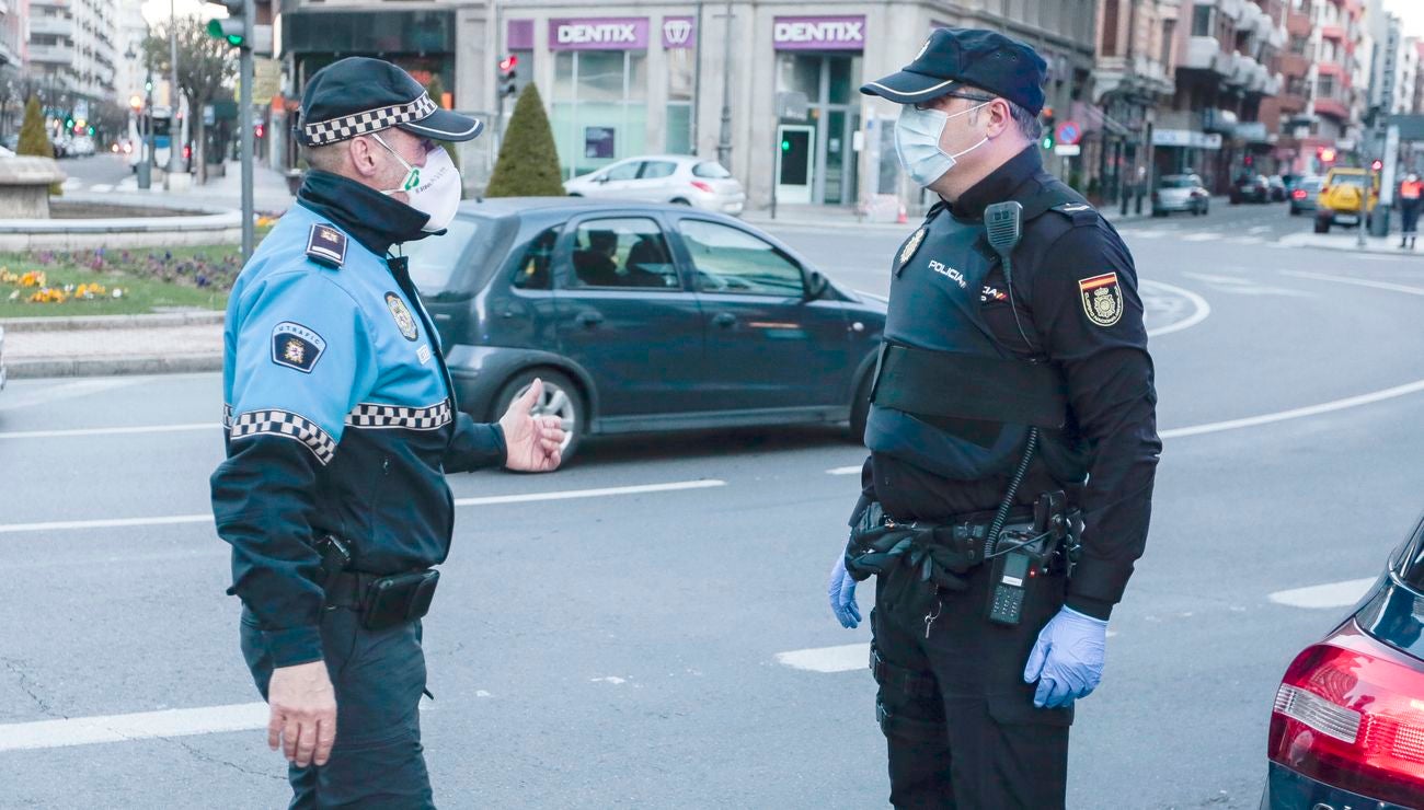 Miembros de Policía Local, Policía Nacional y Protección Civil de León, reparten mascarillas a usuarios del transporte público.