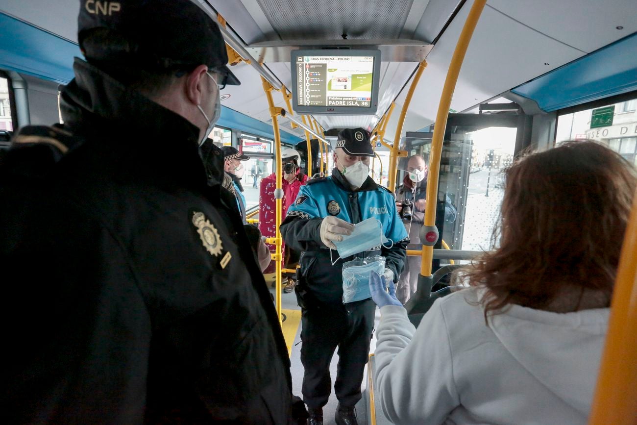 Miembros de Policía Local, Policía Nacional y Protección Civil de León, reparten mascarillas a usuarios del transporte público.