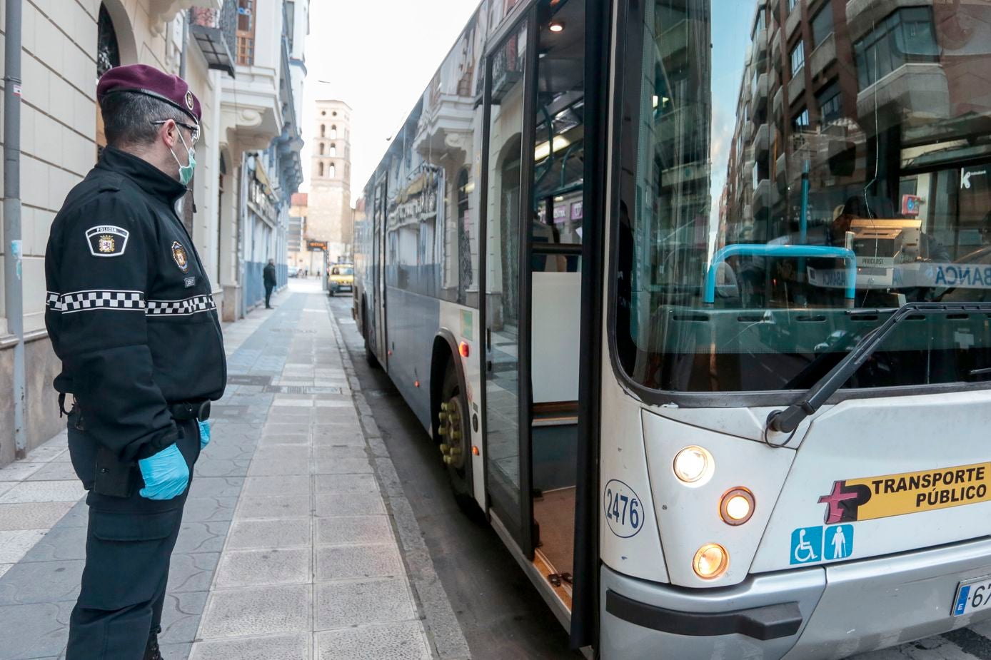 Miembros de Policía Local, Policía Nacional y Protección Civil de León, reparten mascarillas a usuarios del transporte público.