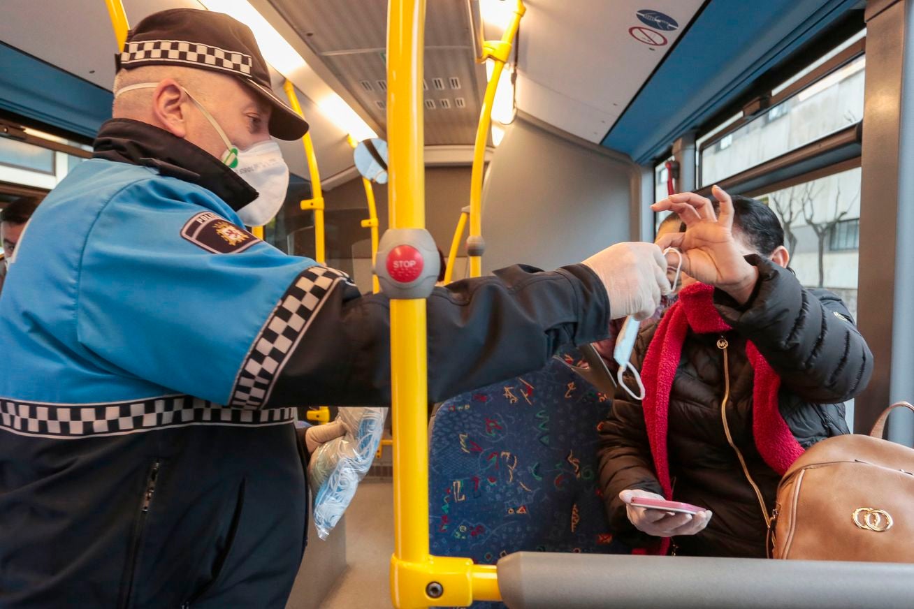 Miembros de Policía Local, Policía Nacional y Protección Civil de León, reparten mascarillas a usuarios del transporte público.