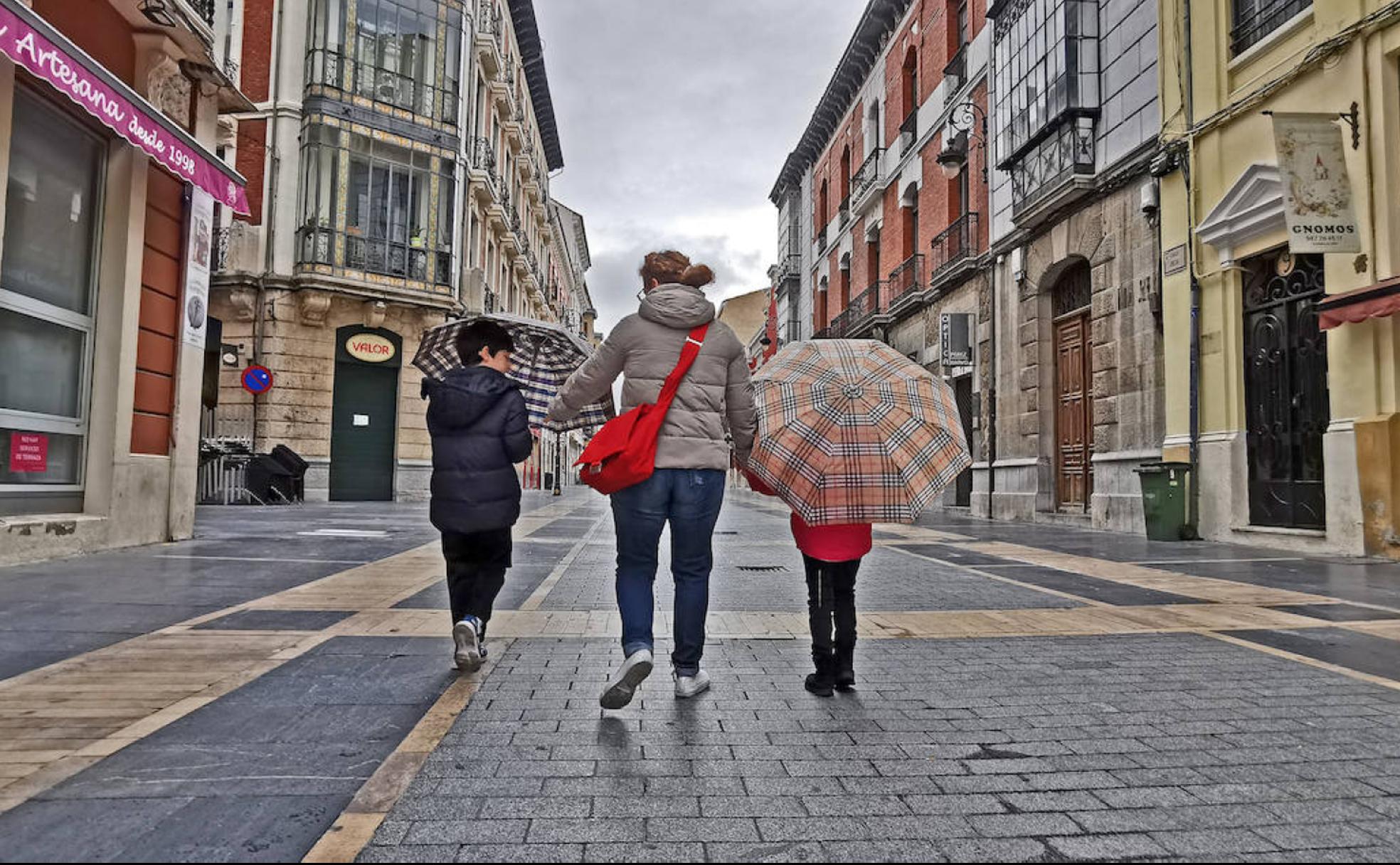 Dos niños pasean junto a su madre en la calle Ancha de León.