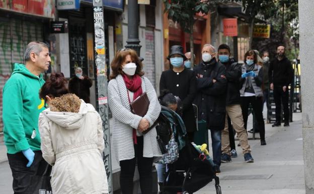 Cola de personas que esperan turno para hacer la compra en Madrid. 