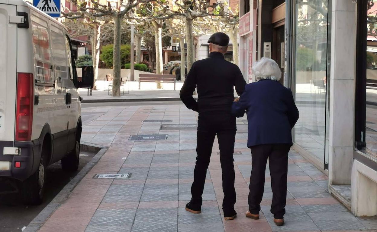 Dos personas pasean por las calles de León.