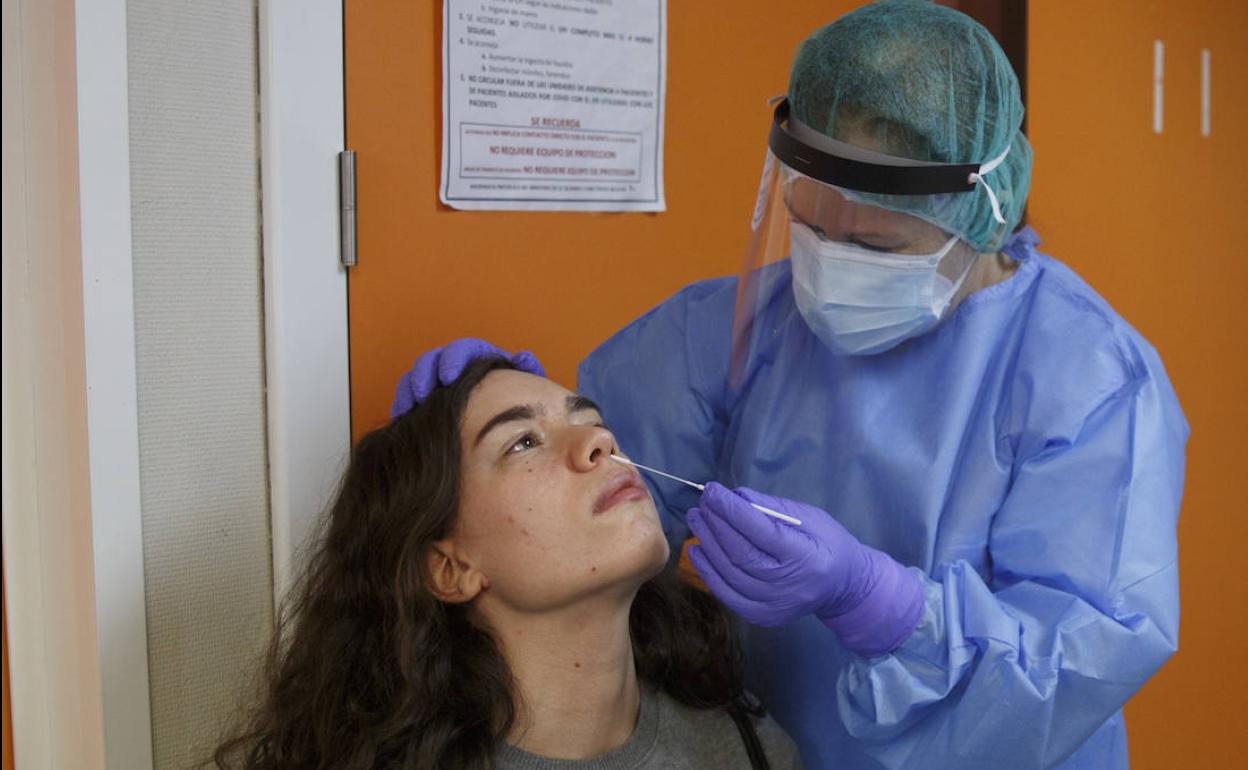 Una enfermera toma una muestra para una PCR a una paciente. 