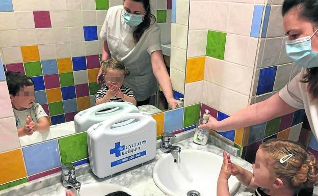 Inés Suárez, directora de la guardería Barrio Sésamo de Gijón, ayuda a dos pequeños a lavarse las manos con agua y jabón. 