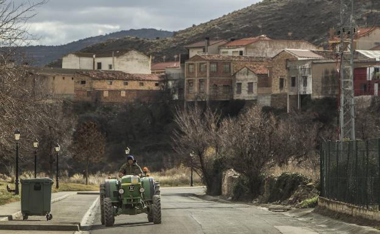 Un tractor circula por la calle de un pueblo. 