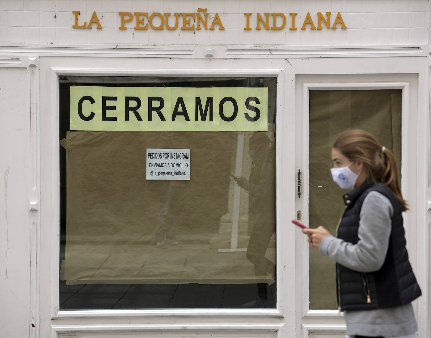 Una mujer pasea ante un negocio cerrado en Burgos. 