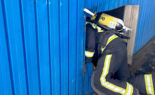 Un bombero atraviesa una puerta para comprobar el estado del incendio.