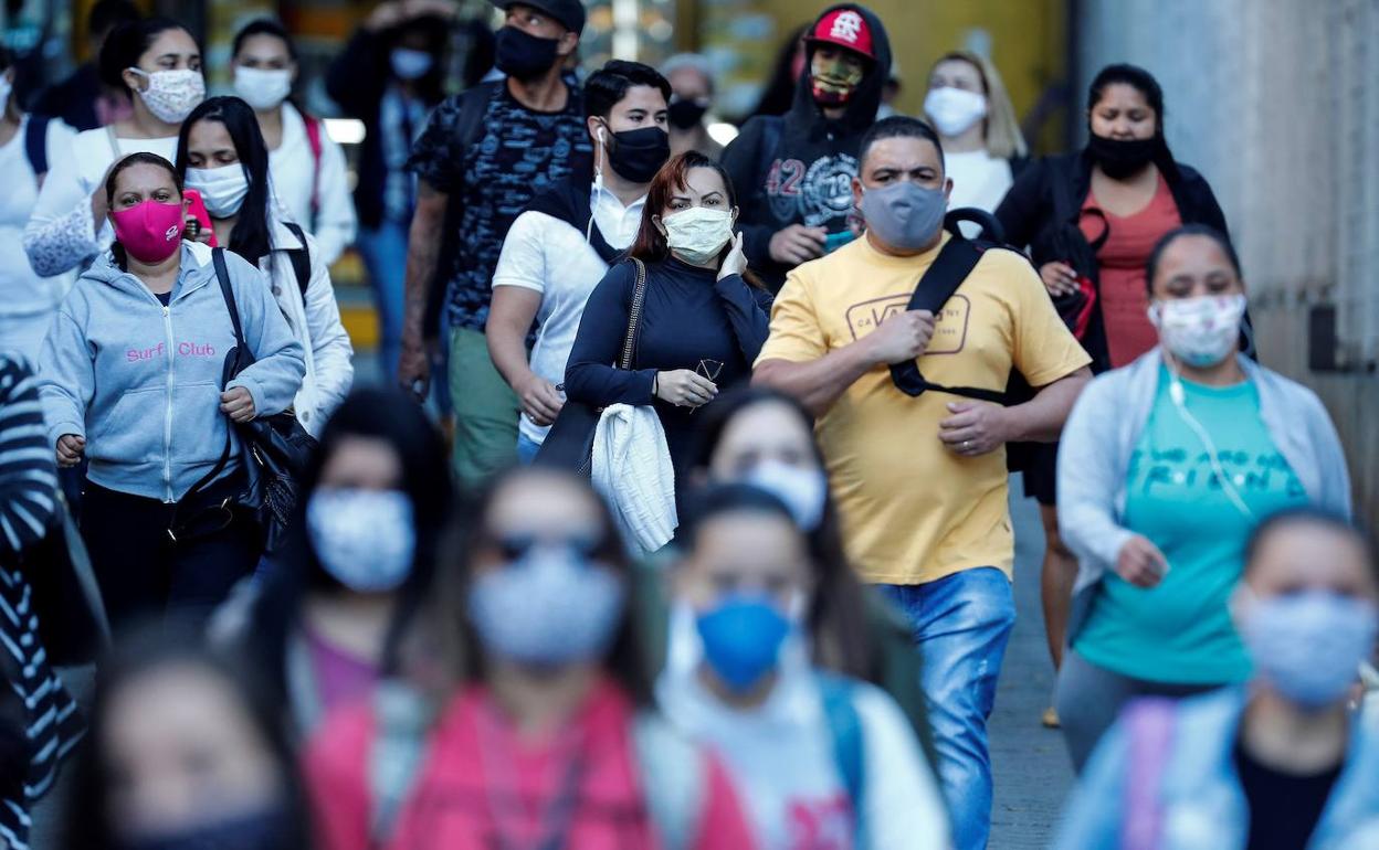 Los ciudadanos, protegidos con mascarilla, en una calle de Sao Paulo (Brasil).