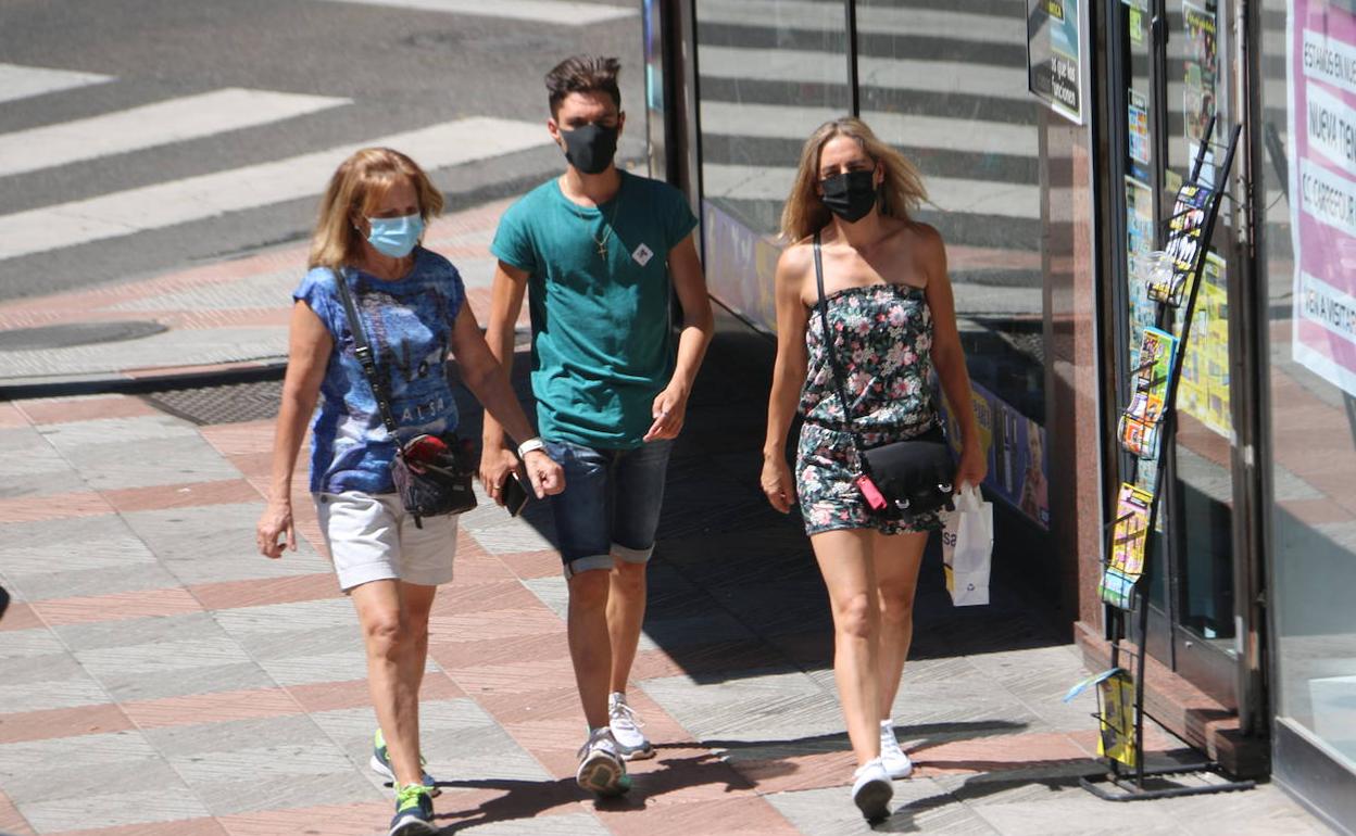 Tras personas caminan con mascarilla en León. 