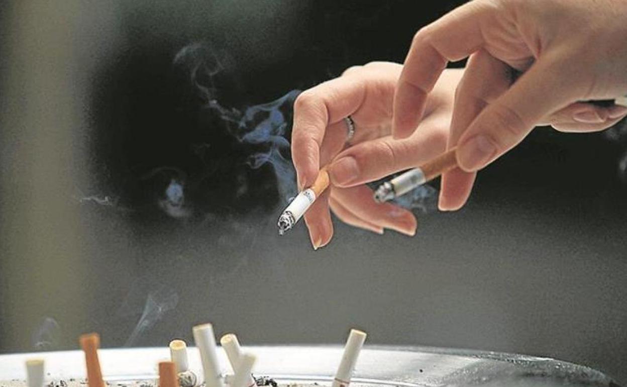 Dos personas tiran las colillas en una papelera.