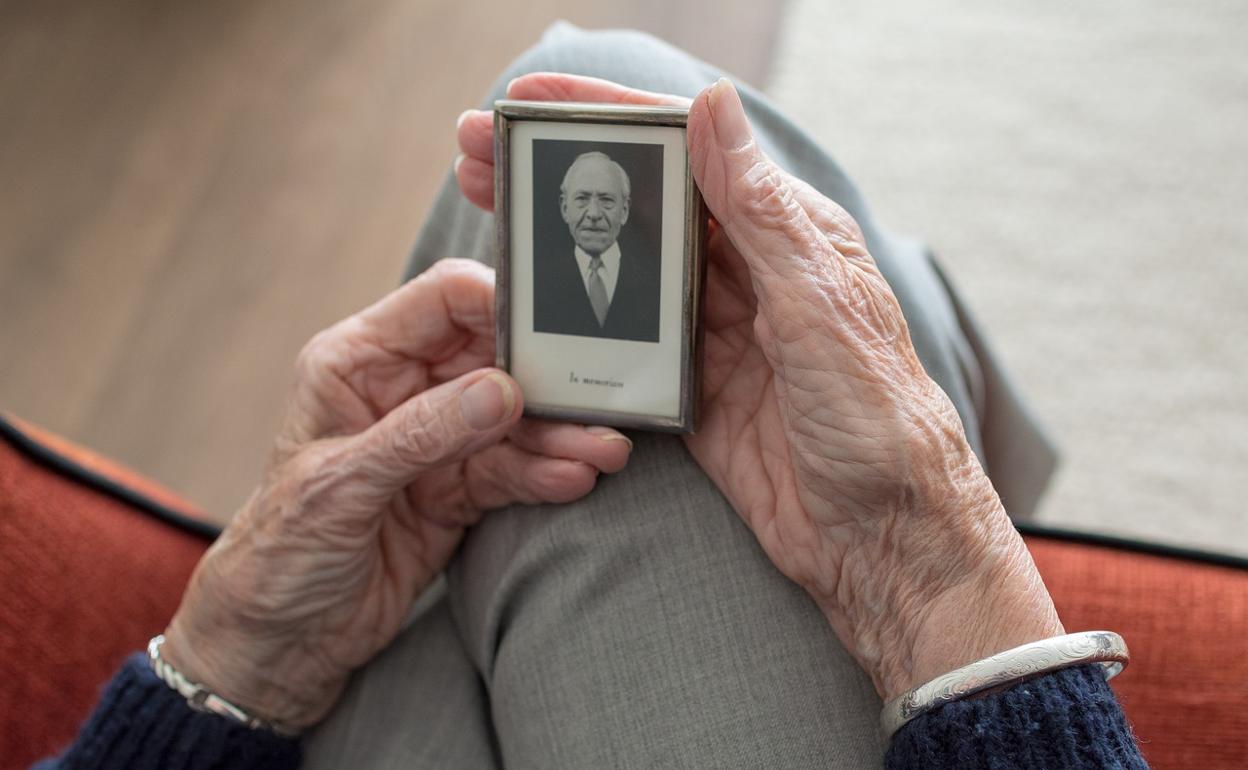 Una mujer sujeta en sus manos la foto de su marido. 