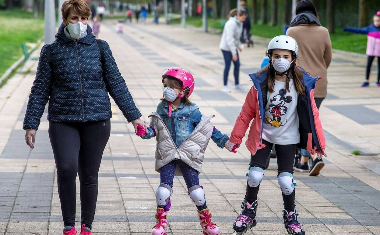 Un adulto acompaña a dos niñas con mascarilla.