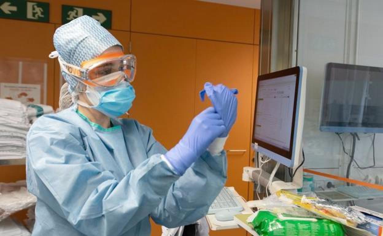 Una sanitaria prepara su traje en una zona de covid.