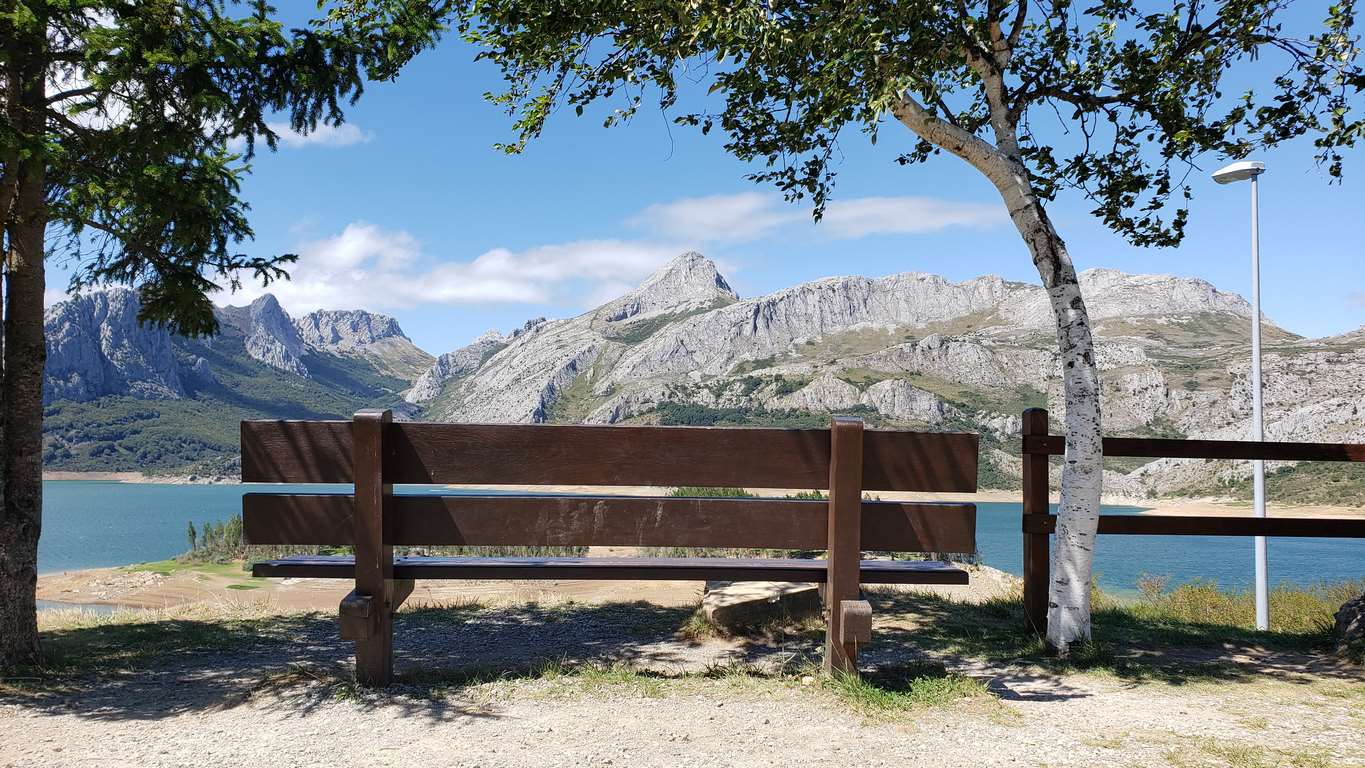 Ubicado junto a la Ermita de Nuestra Señora, en Riaño, el banco ofrece unas privilegiadas vistas sobre el pantano y Picos | El entorno, con las viejas campanas y un 'horreo leonés', completa un escenario idílico. 