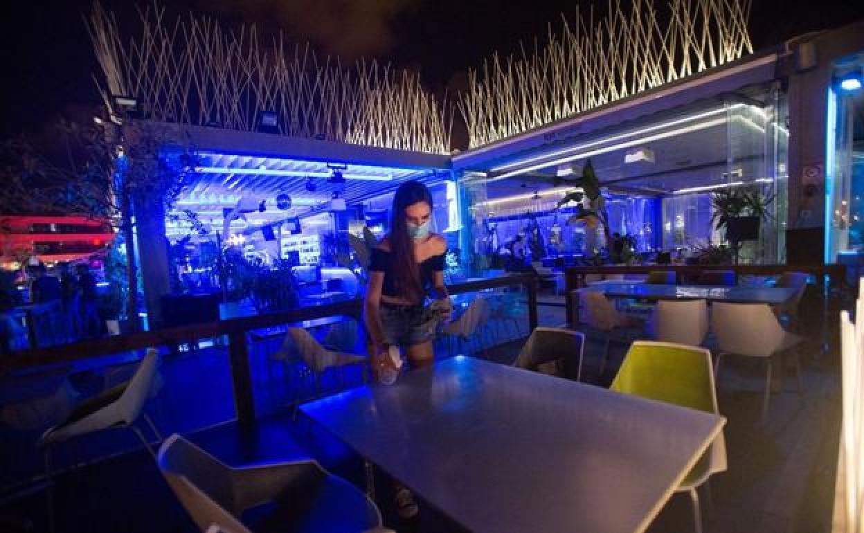 Una camarera limpia una mesa de un local nocturno. 