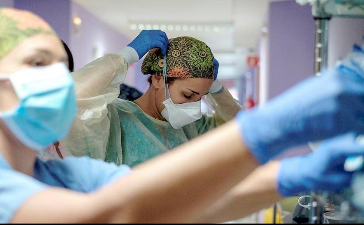 Una sanitaria se prepara para atender a un paciente. 