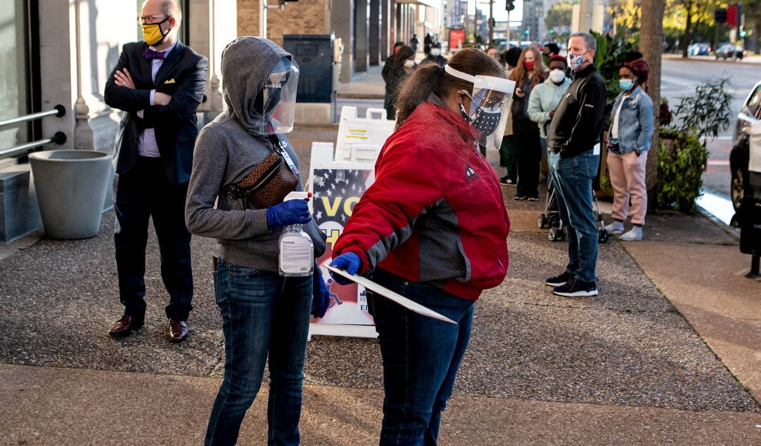 Los trabajadores electorales se desinfectan después de que un votante con coronavirus dejara su voto en la acera para prevenir la propagación del virus en St. Louis, Missouri.