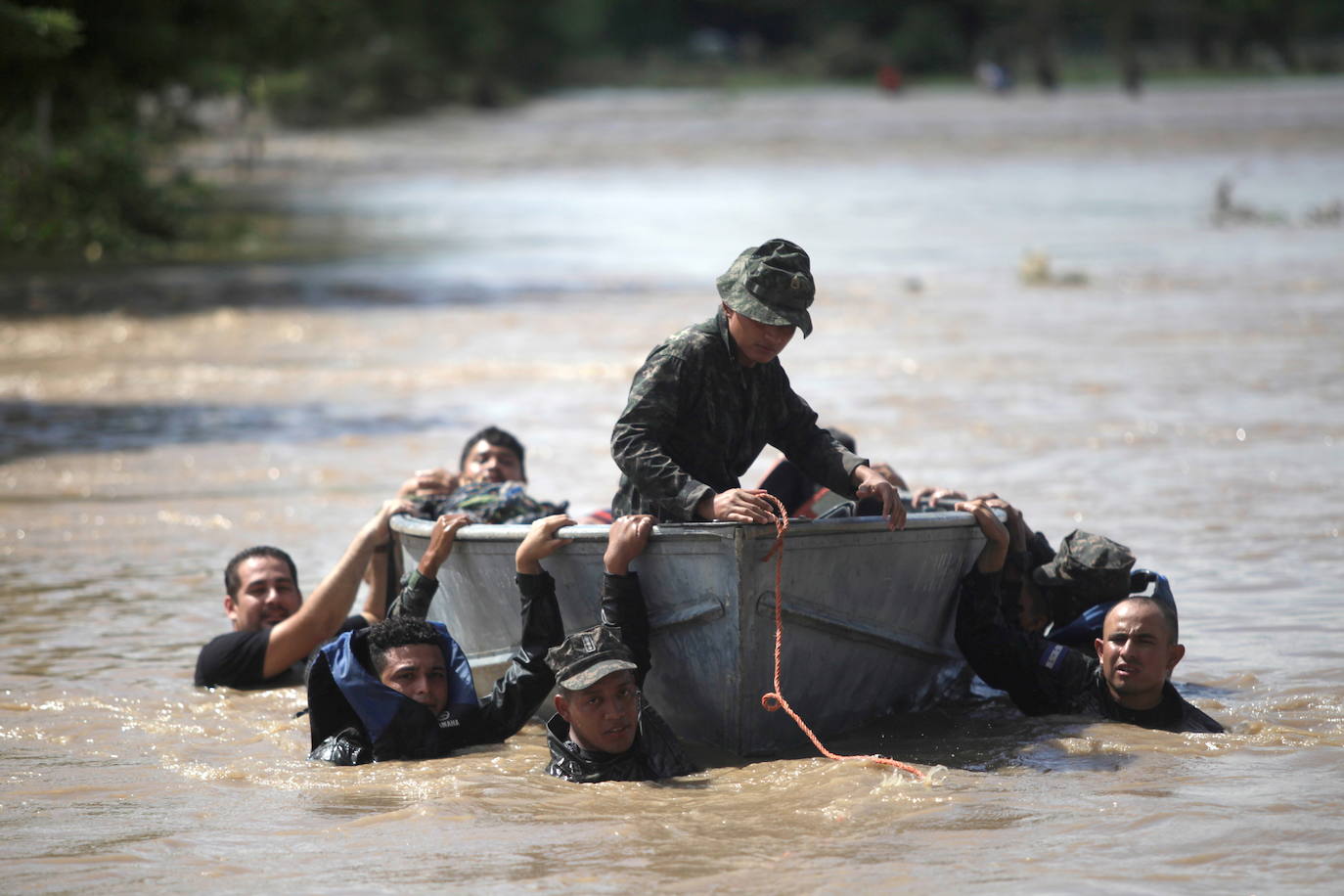 Los soldados se aferran a un bote para cruzar una calle inundada después del paso de la tormenta Eta.